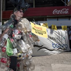 Personas protestan arrojando botellas de plástico vacías recogidas de un río contaminado frente a una fábrica de Coca-Cola en Rosario, Argentina. | Foto:MARCELO MANERA / AFP
