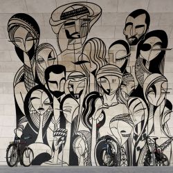 Un hombre pasa junto a una obra de arte titulada "Reunión familiar" de Abdulaziz Yousef Ahmed en la pared de la estación de metro de Msheireb en Doha, Qatar. | Foto:ADRIAN DENNIS / AFP