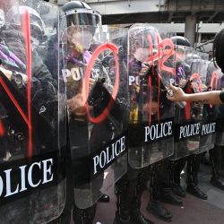 Un manifestante pinta con spray escudos sostenidos por la policía antidisturbios durante una protesta cerca del lugar de la cumbre de la Cooperación Económica Asia-Pacífico (APEC) en Bangkok, Tailandia. | Foto:LILLIAN SUWANRUMPHA / AFP