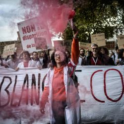 Una mujer sostiene una bengala roja mientras internos y estudiantes de medicina participan en una concentración el día de la huelga organizada por varios sindicatos para protestar por la ampliación de un año de la formación de médicos generales en zonas geográficas que sufren escasez de personal médico, en Lyon, Francia. | Foto:JEFF PACHOUD / AFP