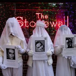 Manifestantes de "Gays contra las armas" sostienen retratos de las víctimas de tiroteos masivos, durante una vigilia en el Día de la Memoria Trans en The Stonewall Inn en la ciudad de Nueva York. | Foto:YUKI IWAMURA / AFP