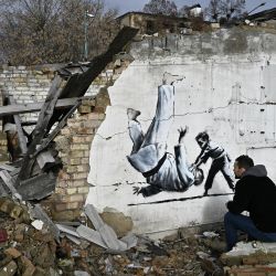 Un residente local mira un grafiti al estilo de Banksy en la pared de un edificio destruido, pero su origen sigue sin ser confirmado por el artista, en Borodyanka, cerca de Kyiv, en medio de la invasión rusa de Ucrania. | Foto:GENYA SAVILOV / AFP