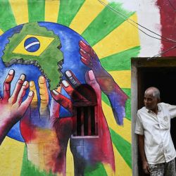 Un hombre gesticula junto a un grafiti en la pared para celebrar el torneo de fútbol de la Copa Mundial de la FIFA Qatar 2022, en Calcuta, India. | Foto:DIBYANGSHU SARKAR / AFP