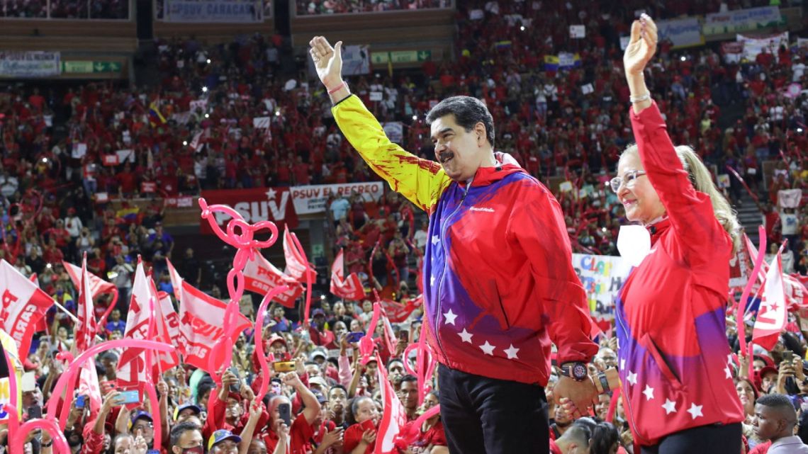 This handout photo released by Miraflores Presidential Palace Press Office shows Venezuela's President Nicolás Maduro and his wife, Cilia Flores, waving to the crowd during the swearing-in of the elected structure of the ruling United Socialist Party of Venezuela (PSUV) as part of preparations for the upcoming 2023 internal elections in Caracas on November 17, 2022. 