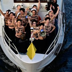 Activistas del grupo activista feminista Femen gritan consignas mientras se encuentran en un barco en el río Spree durante una acción de protesta en el Día Internacional de la Eliminación de la Violencia contra la Mujer, en el centro de la capital alemana, Berlín. | Foto:JOHN MACDOUGALL / AFP