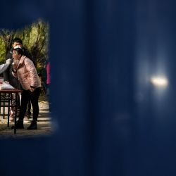 Un trabajador de la salud toma una muestra de hisopo de una mujer en una zona residencial bajo bloqueo debido a las restricciones del coronavirus Covid-19 en Beijing, China. | Foto:Noel Celis / AFP