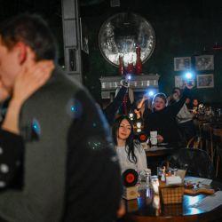 Una pareja se besa en un bar durante un corte de luz en Kiev, en medio de la invasión rusa de Ucrania. | Foto:BULENT KILIC / AFP