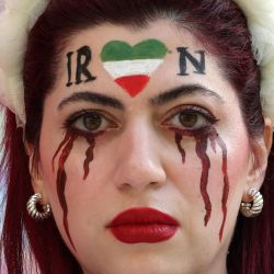 Una simpatizante de Irán con la cara maquillada para mostrar lágrimas de sangre bajo un corazón con los colores iraníes, posa para las fotografías antes del partido de fútbol del Grupo B de la Copa Mundial de Qatar 2022 entre Gales e Irán en el estadio Ahmad Bin Ali en Al-Rayyan, al oeste de Doha. - Irán se ha visto sacudido por más de siete semanas de protestas en todo el país por la muerte de la joven kurda iraní de 22 años Masha Amini mientras estaba bajo la custodia de la policía de la moralidad de Teherán. | Foto:GIUSEPPE CACACE / AFP
