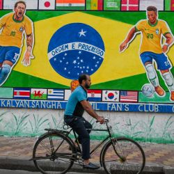 Unos transeúntes cruzan un muro de la carretera pintado con murales en apoyo de la selección brasileña de fútbol para el Mundial de Qatar 2022, en Calcuta, India. | Foto:DIBYANGSHU SARKAR / AFP