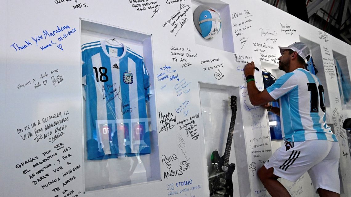A fan of Argentina's Diego Maradona signs his name as he pays tribute on the second anniversary of Maradona's death at a fan zone devoted to the Argentine at Doha's international airport on November 25, 2022. Maradona died of a heart attack on November 25, 2020 at the age of 60, setting off a wave of deep mourning across the football world. 