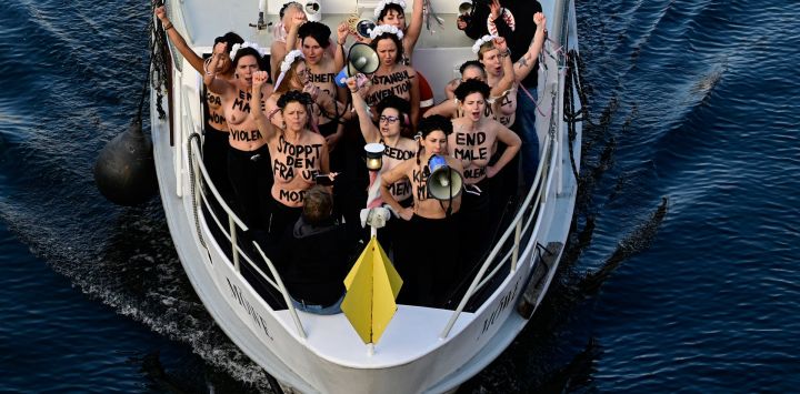 Activistas del grupo activista feminista Femen gritan consignas mientras se encuentran en un barco en el río Spree durante una acción de protesta en el Día Internacional de la Eliminación de la Violencia contra la Mujer, en el centro de la capital alemana, Berlín.