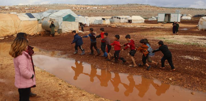 Los niños juegan alrededor de los charcos de agua después de las fuertes lluvias, en el campo de desplazados de Kafr Arouk, en el campo norte de la provincia siria de Idlib, controlado por los rebeldes.