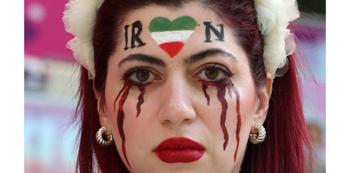 Una simpatizante de Irán con la cara maquillada para mostrar lágrimas de sangre bajo un corazón con los colores iraníes, posa para las fotografías antes del partido de fútbol del Grupo B de la Copa Mundial de Qatar 2022 entre Gales e Irán en el estadio Ahmad Bin Ali en Al-Rayyan, al oeste de Doha. - Irán se ha visto sacudido por más de siete semanas de protestas en todo el país por la muerte de la joven kurda iraní de 22 años Masha Amini mientras estaba bajo la custodia de la policía de la moralidad de Teherán.