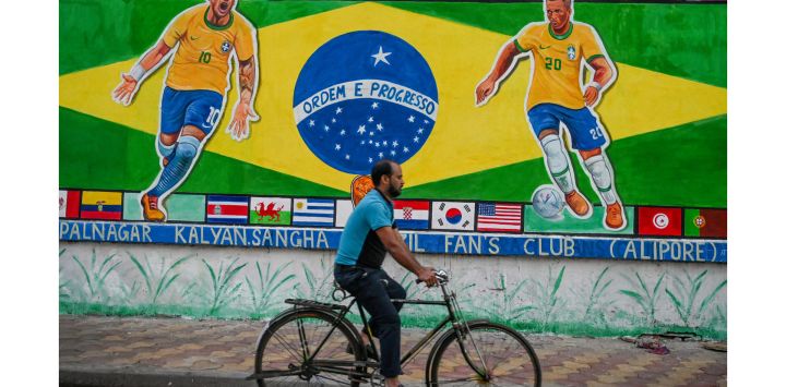 Unos transeúntes cruzan un muro de la carretera pintado con murales en apoyo de la selección brasileña de fútbol para el Mundial de Qatar 2022, en Calcuta, India.