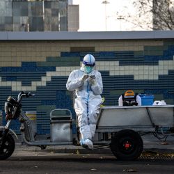 Un trabajador con equipo de protección personal (EPP) utiliza un teléfono móvil en una calle de Pekín, China. | Foto:Noel Celis / AFP