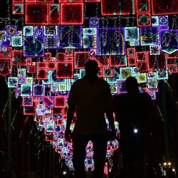 Personas vistas en silueta bajo la iluminación de las calles en el paseo de la Corniche en Doha, durante el torneo de fútbol de la Copa del Mundo Qatar 2022. | Foto:JUAN MABROMATA / AFP