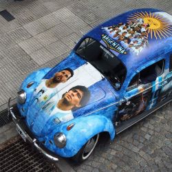 Vista de un Volkswagen 1960 pintado con imágenes de jugadores de la selección argentina de fútbol en Buenos Aires. - El coche fue diseñado por la diseñadora Luz Baliña y es propiedad de su padre Carlos, como un proyecto familiar. | Foto:LUIS ROBAYO / AFP
