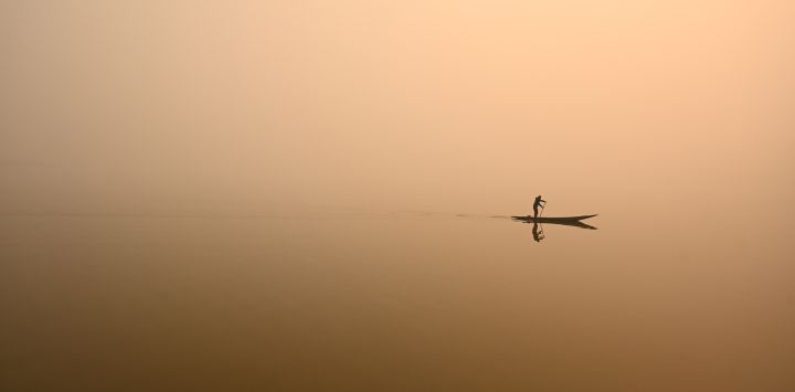 Un hombre dirige una barca en el lago Dal en medio de un espeso manto de niebla en Srinagar, India.