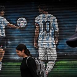 La gente pasa por delante de un mural del artista Causi que representa a las estrellas del fútbol argentino Lionel Messi y el fallecido Diego Maradona en Buenos Aires. | Foto:LUIS ROBAYO / AFP