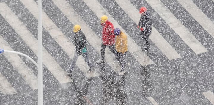 La gente camina por una carretera durante una nevada en Yantai, en la provincia oriental china de Shandong.