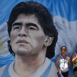 Miembros de organizaciones sociales junto a un mural que representa al fallecido astro del fútbol argentino Diego Maradona durante una protesta en el puente Pueyrredón en Buenos Aires. | Foto:LUIS ROBAYO / AFP