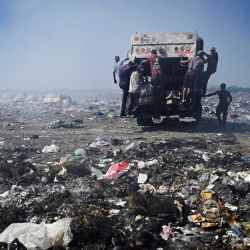 Recicladores se cuelgan de un camión de basura, en el vertedero de Luján, Argentina. - Decenas de personas buscan entre la basura objetos reciclables que venden para el sustento de sus hogares y como forma de hacer frente a la crisis económica del país. El vertedero de Luján, el más grande a cielo abierto de Argentina, se transformará en un centro medioambiental, poniendo fin a años de contaminación, insalubridad y también a la forma de ganarse la vida de estos recicladores. | Foto:LUIS ROBAYO / AFP