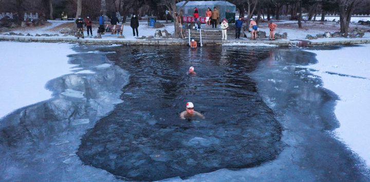 Esta foto muestra a entusiastas de la natación de invierno nadando en un lago parcialmente congelado después de una nevada en Shenyang, en la provincia nororiental china de Liaoning.