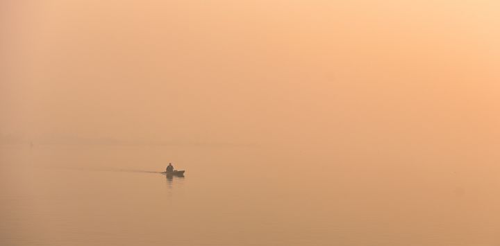 Un hombre dirige una barca en el lago Dal en medio de la niebla en Srinagar, India.