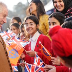 El rey Carlos III de Gran Bretaña se reúne con escolares que ondean banderas durante su visita a la recién construida Guru Nanak Gurdwara, en Luton, al norte de Londres. | Foto:Chris Jackson / POOL / AFP