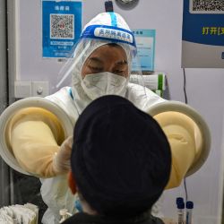 Un trabajador de la salud toma una muestra de hisopo de un hombre para analizar el coronavirus Covid-19 en el distrito de Jing'an en Shanghái, China. | Foto:HECTOR RETAMAL / AFP