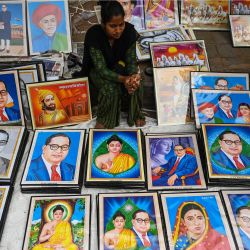 Una mujer se sienta en un puesto para vender fotos de Bhimrao Ambedkar y el Señor Gautam Buda en el 66 aniversario de la muerte de Ambedkar cerca de su monumento Chaitya Bhoomi en Mumbai, India. | Foto:PUNIT PARANJPE / AFP