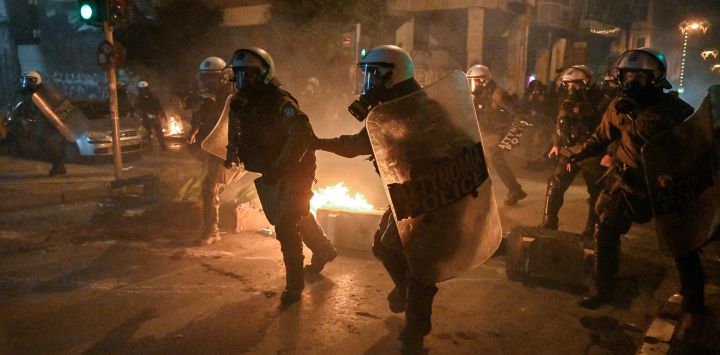 La policía persigue a manifestantes durante los enfrentamientos que se produjeron al margen de una concentración contra la violencia policial, con motivo del 14º aniversario de la muerte de un adolescente en 2008 por disparos de la policía en el barrio de Exarchia, en el centro de Atenas, Grecia.