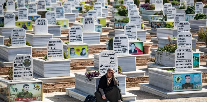 Un doliente se sienta en un cementerio cerca del cortejo fúnebre de un combatiente de las Unidades de Protección del Pueblo Kurdo (YPG), en la ciudad de mayoría kurda de Qamishli, en el noreste de Siria.