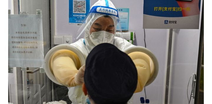 Un trabajador de la salud toma una muestra de hisopo de un hombre para analizar el coronavirus Covid-19 en el distrito de Jing'an en Shanghái, China.