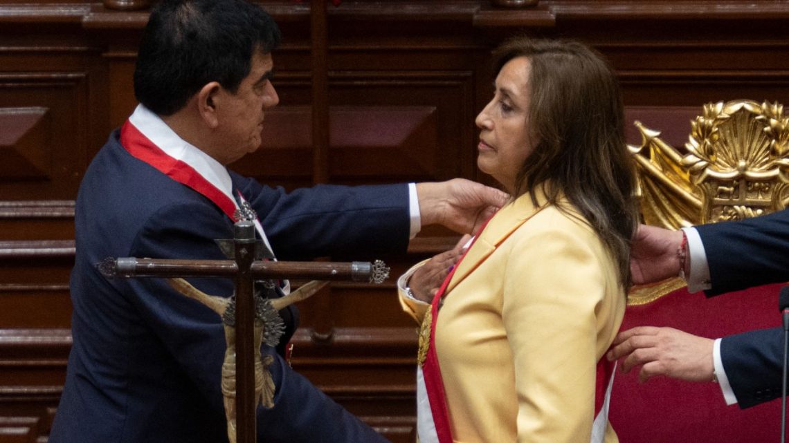Dina Boluarte accepts the presidential baton and sash.
