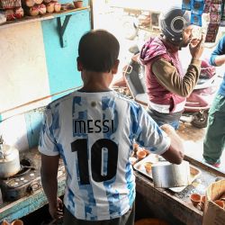 El propietario de un puesto de té, Shib Shankar Patra, aficionado a la selección argentina de fútbol, lleva una camiseta de Messi mientras trabaja en su puesto de té pintado con los colores del equipo en Ichhapur, a unos 35 km al norte de Calcuta, en India. | Foto:DIBYANGSHU SARKAR / AFP