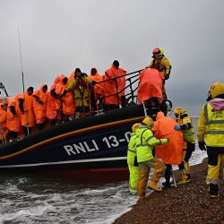 Migrantes, recogidos en el mar intentando cruzar el Canal de la Mancha, son ayudados a desembarcar desde un bote salvavidas de la Royal National Lifeboat Institution (RNLI), en Dungeness, en la costa sureste de Inglaterra. | Foto:Ben Stansall / AFP