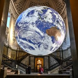 Visitantes observan la obra de arte "Gaia", creada por el artista visual británico Luke Jerram, que se expone en la bóveda sur del Palacio Real de Estocolmo, Suecia. - El globo "Gaia" mide siete metros de diámetro y fue creado a partir de imágenes tomadas de fotografías de la NASA de la superficie de la Tierra. Es una de las 22 obras de arte que iluminan Estocolmo durante el festival de la luz "Luces de la Semana Nobel". | Foto:ANDERS WIKLUND / Agencia de noticias TT / AFP
