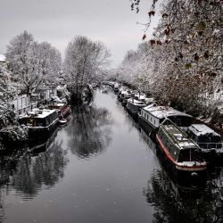 La nieve cubre árboles y barcas estrechas a lo largo del Regent's Canal en el este de Londres. - El Reino Unido fue azotado por fuertes nevadas y heladas, causando importantes trastornos en los viajes, en la víspera de una huelga nacional de ferrocarriles que ya se esperaba que paralizara el país. | Foto:ELENA FUSCO / AFP