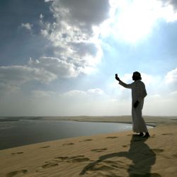 Un hombre toma fotos con su teléfono inteligente en las dunas de Al Wakrah, al sur de Doha, Qatar. | Foto:GABRIEL BOUYS / AFP