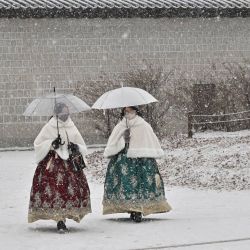 Visitantes vestidos con el tradicional hanbok pasean por el palacio de Gyeongbokgung durante una nevada en el centro de Seúl. | Foto:Jung Yeon-je / AFP