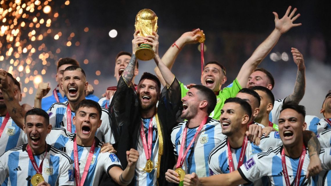 Surrounded by his teammates, Lionel Messi lifts the World Cup trophy during the Qatar 2022 World Cup trophy ceremony after the football final match between Argentina and France at Lusail Stadium in Lusail, north of Doha on December 18, 2022. 