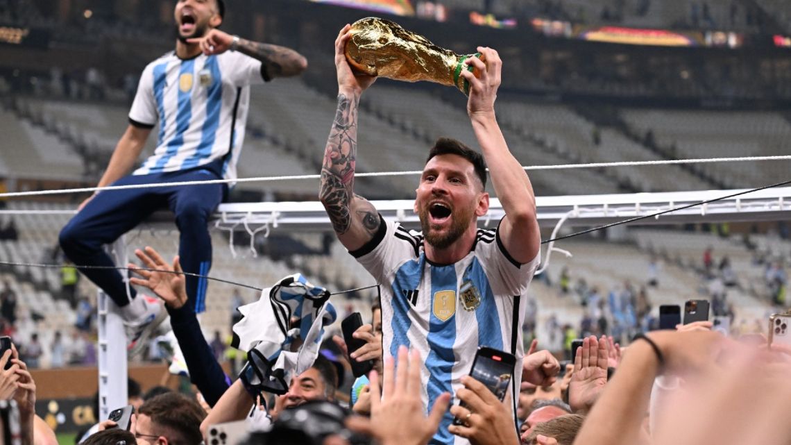 Argentina's forward #10 Lionel Messi lifts the FIFA World Cup Trophy as he celebrateswith supporters winning the Qatar 2022 World Cup final football match between Argentina and France at Lusail Stadium in Lusail, north of Doha on December 18, 2022. 