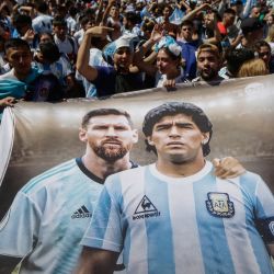 Aficionados de Argentina sostienen una bandera que representa a las estrellas del fútbol argentino Lionel Messi y el fallecido Diego Maradona mientras se reúnen en el Obelisco para celebrar la victoria en la Copa del Mundo Qatar 2022 contra Francia en Buenos Aires. | Foto:EMILIANO LASALVIA / AFP