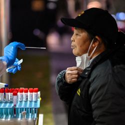 Un trabajador de la salud toma una muestra de hisopo de una mujer para analizar el coronavirus Covid-19 en el distrito de Huangpu en Shanghái, China. | Foto:HECTOR RETAMAL / AFP