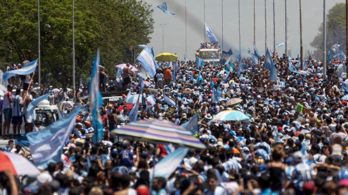 Argentina's players celebrate on board a bus with a sign reading "World Champions" with supporters after winning the Qatar 2022 World Cup tournament as they tour through Buenos Aires' downtown on December 20, 2022. Millions of ecstatic fans are expected to cheer on their heroes as Argentina's World Cup winners led by captain Lionel Messi began their open-top bus parade of the capital Buenos Aires on Tuesday following their sensational victory over France. 