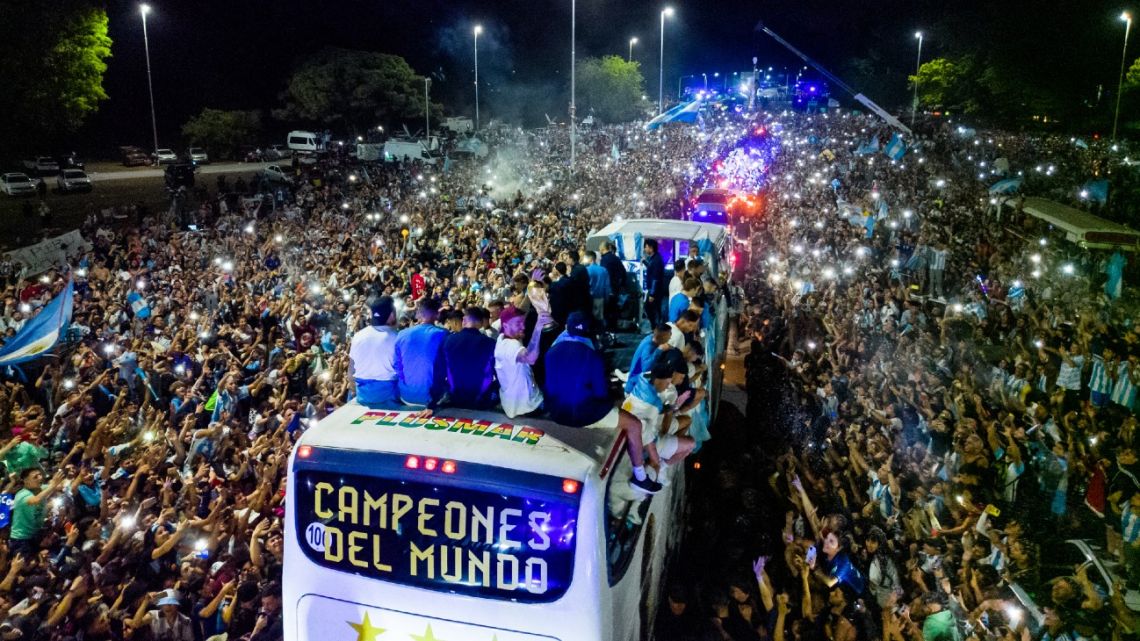 Argentina's players celebrate on board a bus with a sign reading 'World Champions' as supporters greet them after their arrival at Ezeiza International Airport.