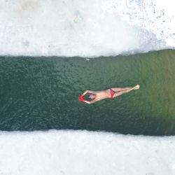 Esta foto aérea muestra a un aficionado a la natación de invierno nadando en un lago parcialmente congelado después de una nevada en Shenyang, en la provincia nororiental china de Liaoning. | Foto:AFP