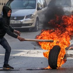 Un joven palestino hace rodar un neumático en llamas en medio de enfrentamientos con las fuerzas de seguridad israelíes tras una protesta por la muerte del preso palestino Nasser Abu Hamed en una prisión israelí en el centro de la ciudad de Hebrón, en Cisjordania ocupada. | Foto:HAZEM BADER / AFP