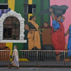 Una mujer pasa junto a una pared recién pintada por el artista Kshetrimayum Johnson Singh como parte del Festival de Arte Urbano en el Muelle Sassoon en Mumbai, India. | Foto:PUNIT PARANJPE / AFP